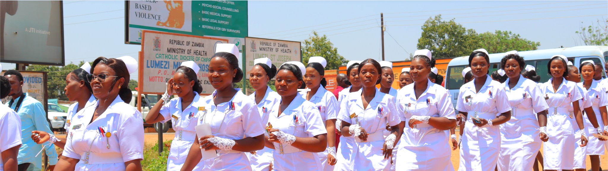 Nursing students in white uniforms walking in procession at Lumezi St. Joseph College of Nursing & Midwifery, Republic of Zambia, Ministry of Health